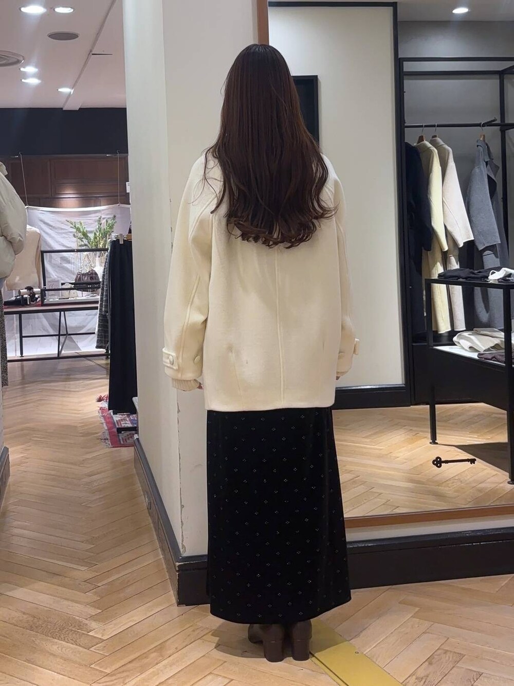 ホワイト系のピーコート、ブラウン系のブーツ、ホワイト系のニット/セーターを着用したレディースの冬コーディネートの3枚目の写真