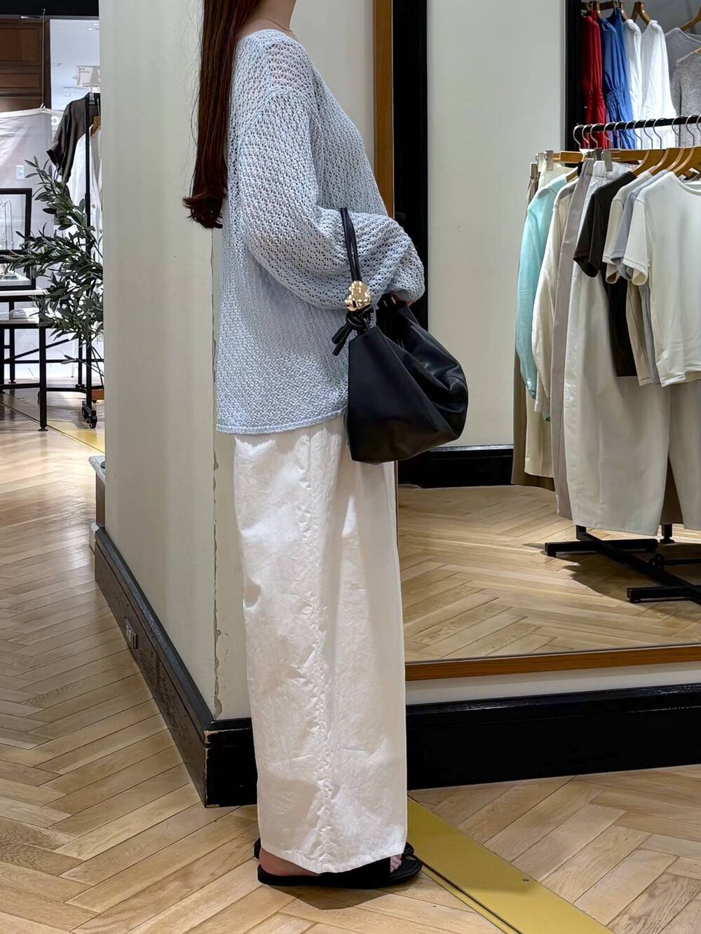 ブラック系のショルダーバッグ、ホワイト系のその他パンツ、ブルー系のニット/セーターを着用したレディースの春コーディネートの2枚目の写真
