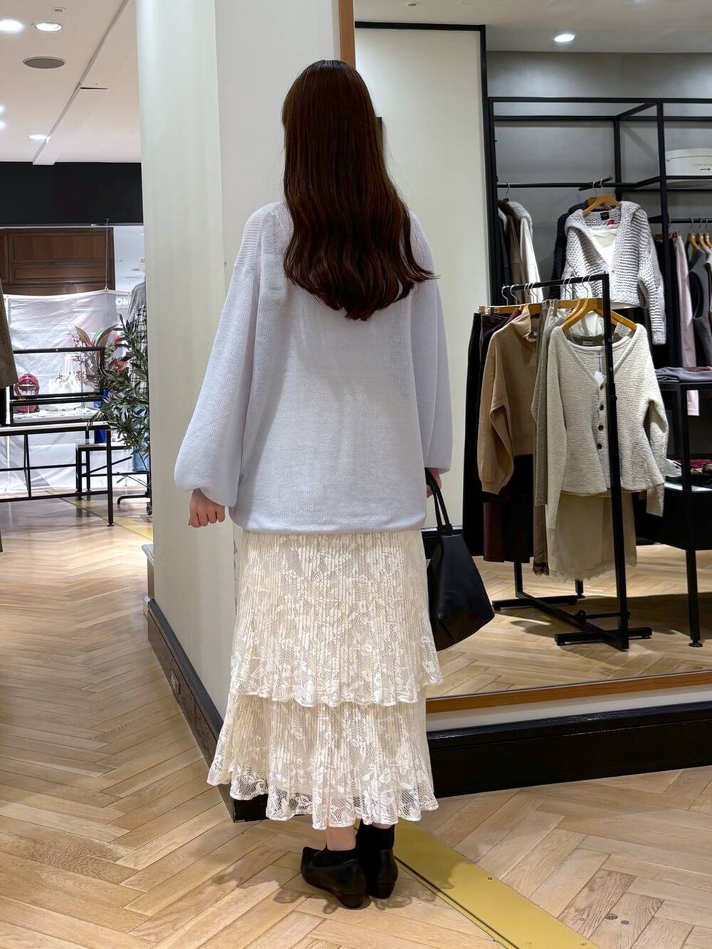 ブラック系のパンプス、ホワイト系のスカート、ブラック系のショルダーバッグを着用したレディースの秋コーディネートの4枚目の写真