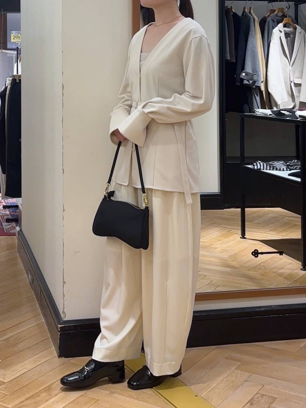 ホワイト系のスラックス、ブラック系のローファー、ブラック系のショルダーバッグを着用したレディースの秋コーディネートの3枚目の写真