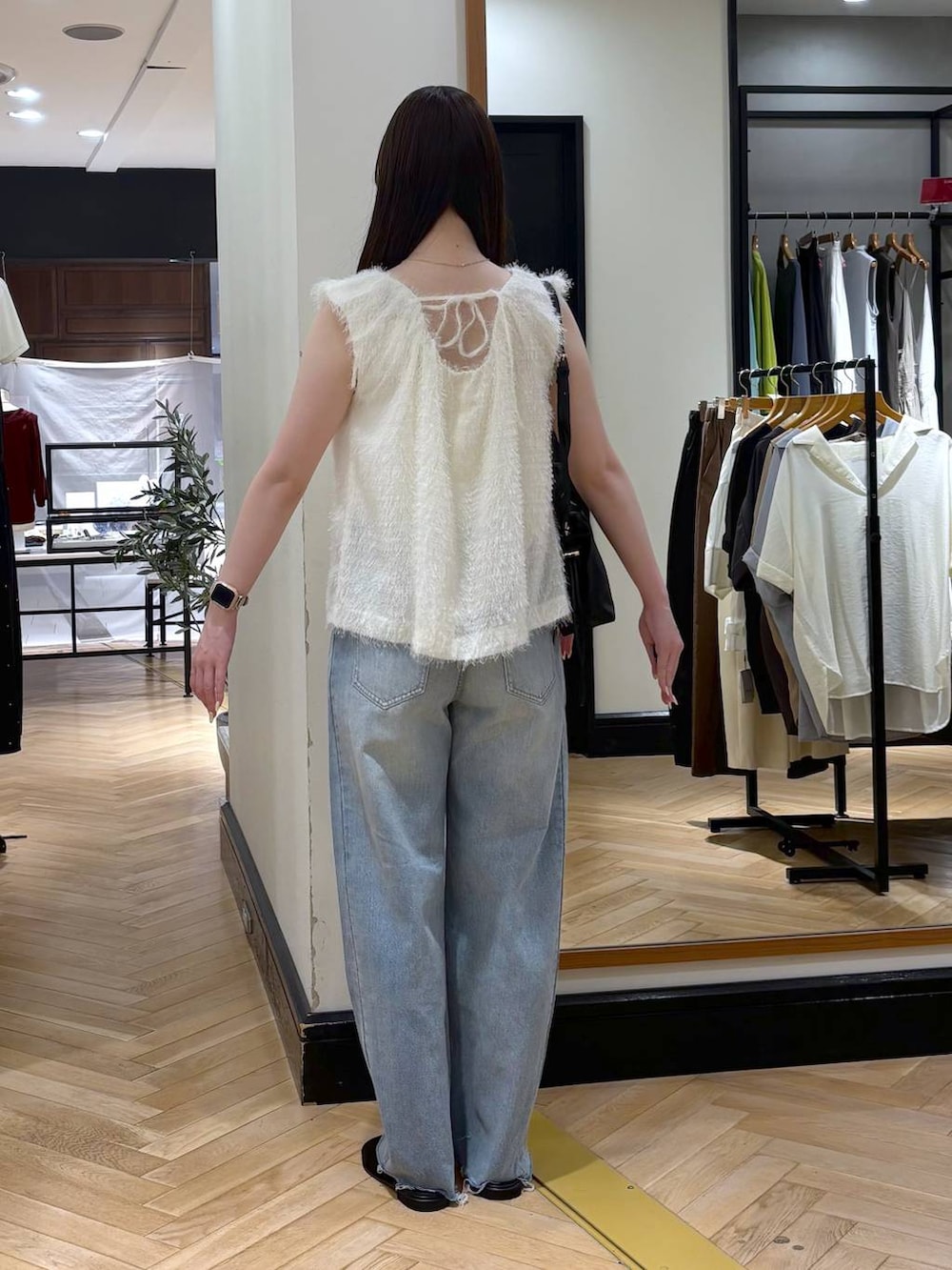 ブラック系のショルダーバッグ、ホワイト系のシャツ/ブラウス、ブルー系のデニムパンツを着用したレディースの夏コーディネートの4枚目の写真