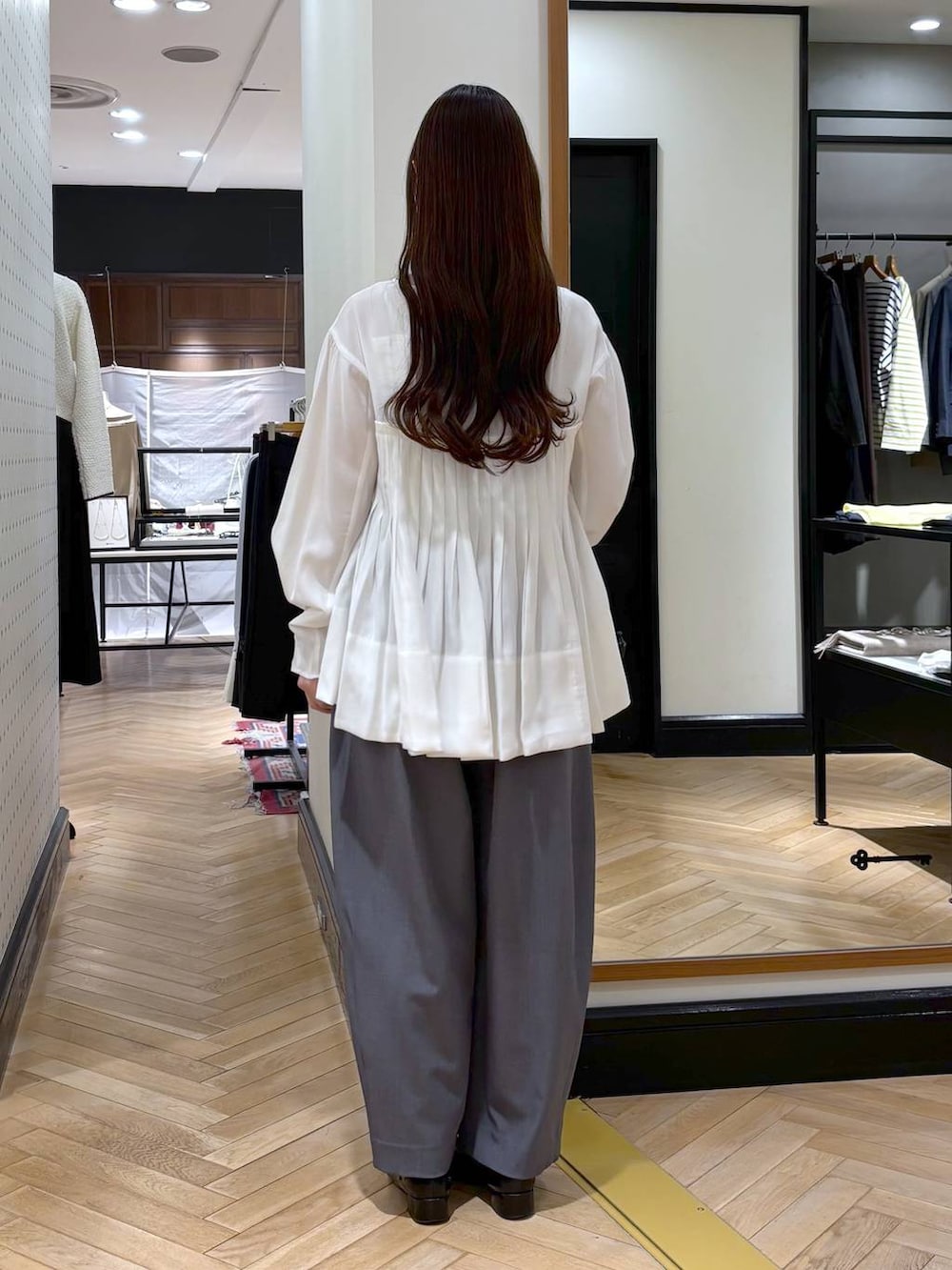 グレー系のスラックス、ブラック系のローファー、ブラック系のショルダーバッグを着用したレディースの冬コーディネートの6枚目の写真