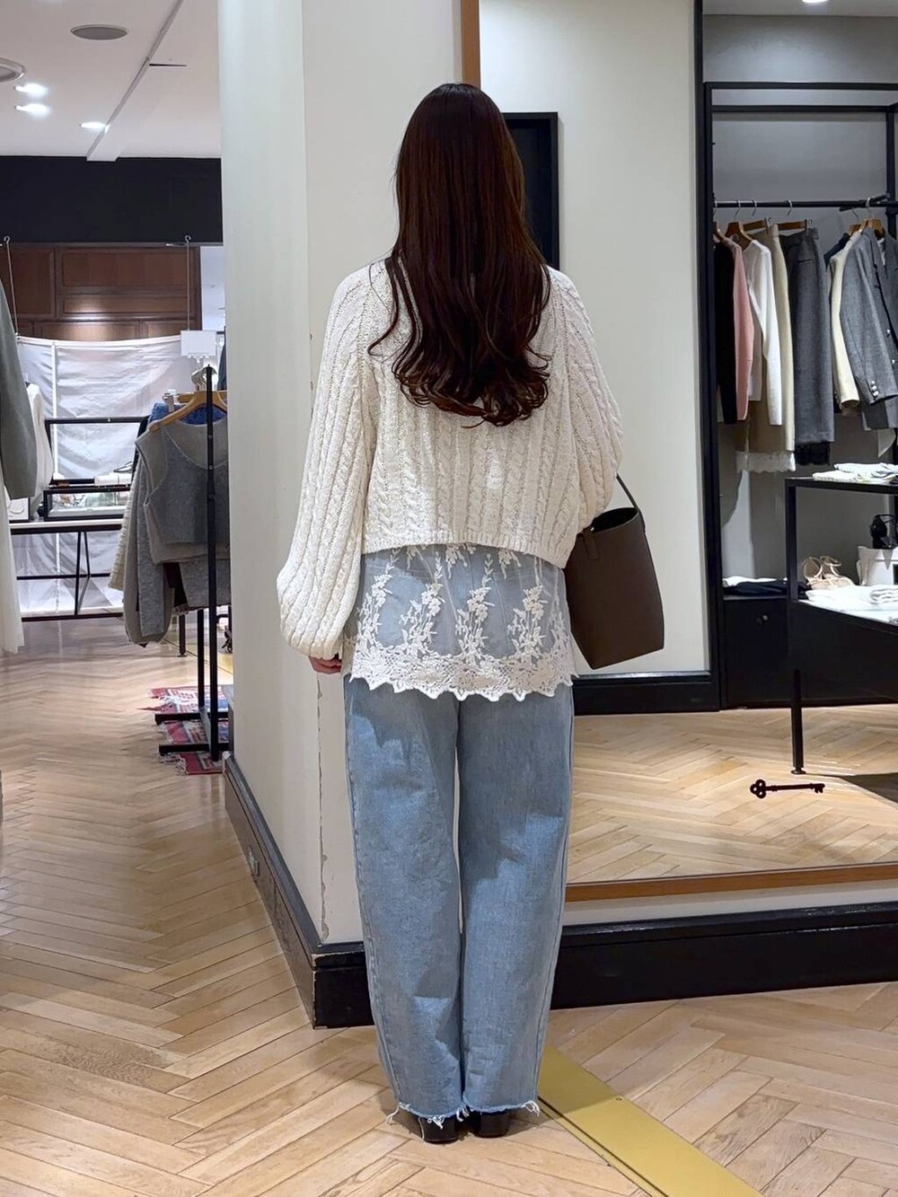 ブラック系のローファー、ホワイト系のチュニック、ブルー系のデニムパンツを着用したレディースの冬コーディネートの3枚目の写真