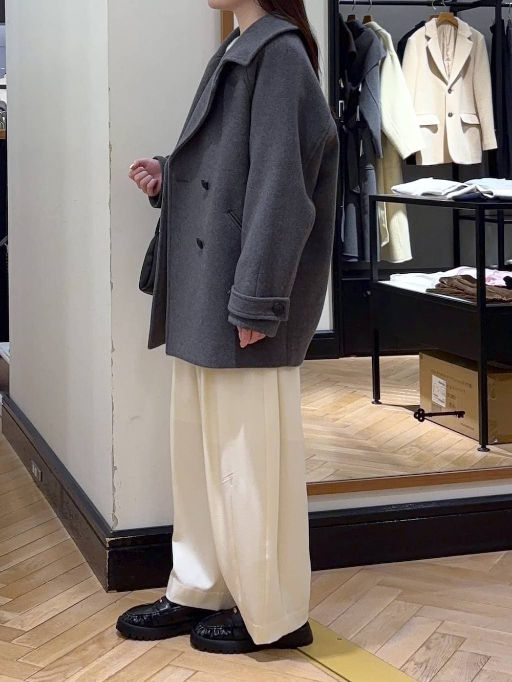 グレー系のピーコート、ホワイト系のスラックス、ブラック系のローファーを着用したレディースの冬コーディネートの3枚目の写真