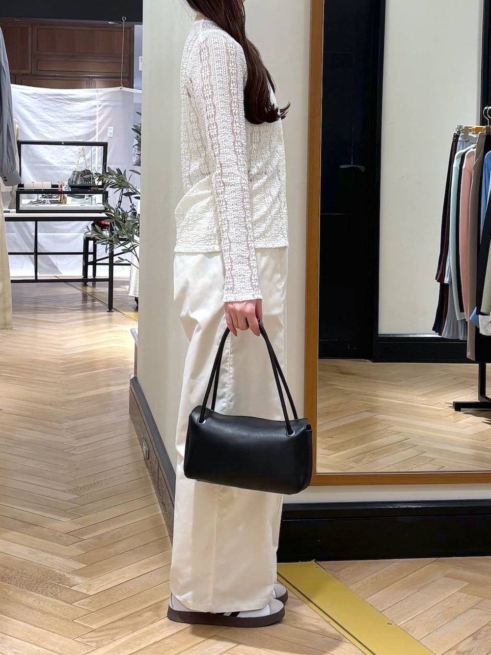 ホワイト系のスラックス、ブラック系のショルダーバッグ、ホワイト系のカーディガン/ボレロを着用したレディースの春コーディネートの3枚目の写真