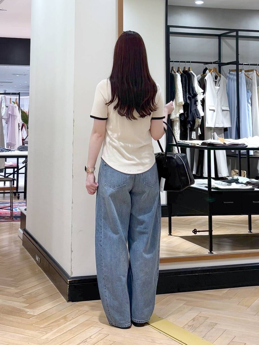 ブルー系のデニムパンツ、ブラック系のボストンバッグ、ブラック系のサンダルを着用したレディースの夏コーディネートの3枚目の写真