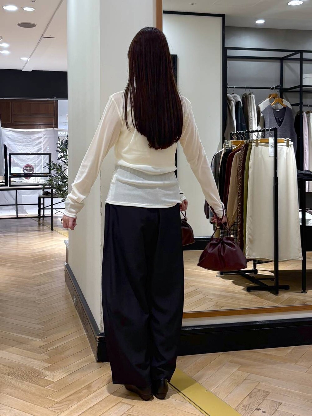 レッド系のショルダーバッグ、ブラック系のパンプス、ホワイト系のキャミソールを着用したレディースの秋コーディネートの4枚目の写真