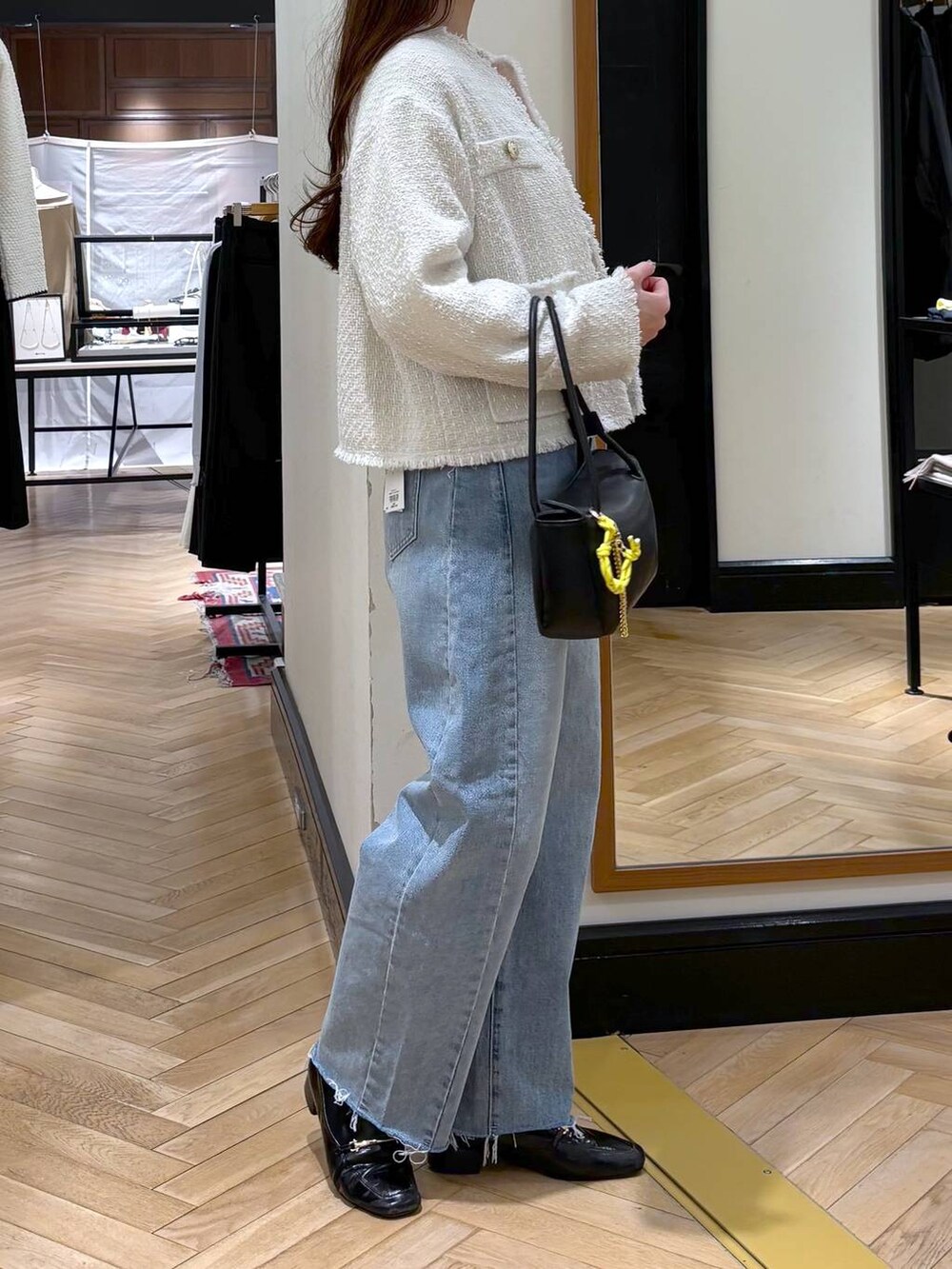 ブラック系のローファー、ブルー系のデニムパンツ、ホワイト系のノーカラージャケットを着用したレディースの冬コーディネートの2枚目の写真