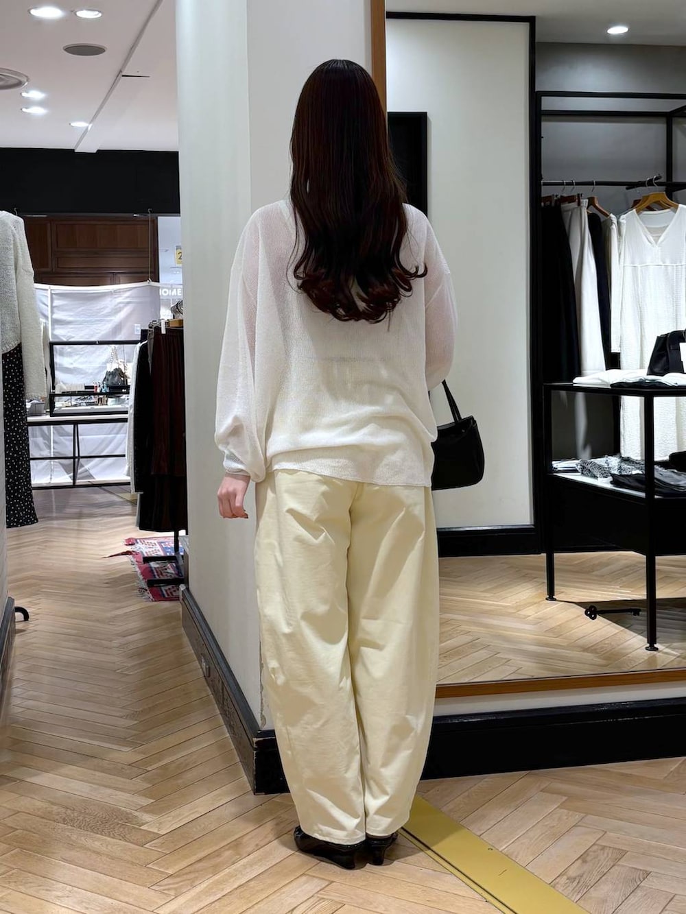 ブラック系のショルダーバッグ、ブラック系のサンダル、ホワイト系のニット/セーターを着用したレディースの春コーディネートの4枚目の写真