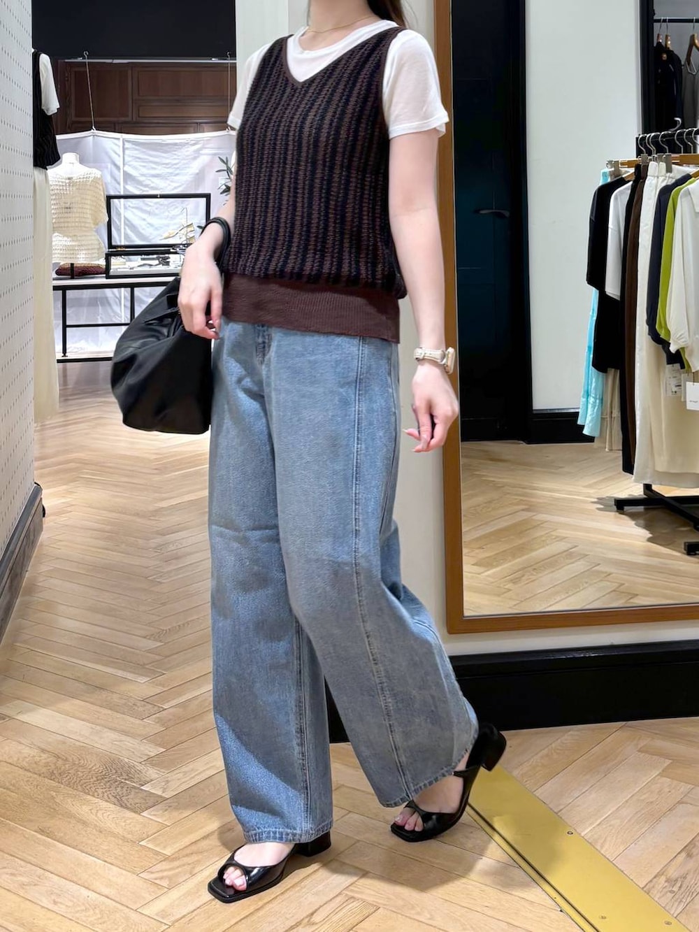 ブラック系のショルダーバッグ、ブルー系のデニムパンツ、ブラック系のパンプスを着用したレディースの夏コーディネートの2枚目の写真