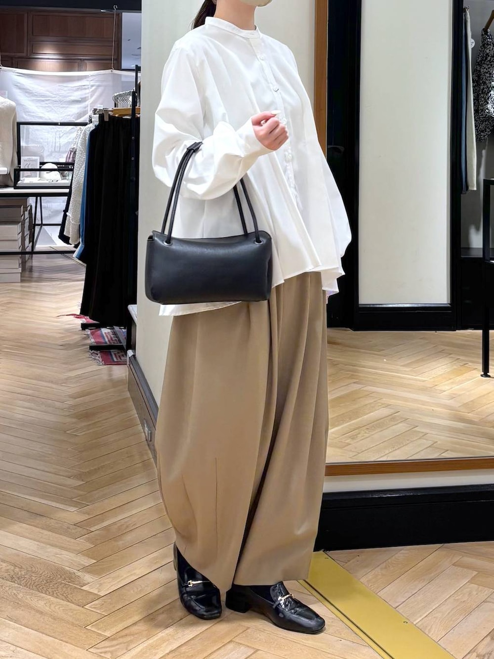 ベージュ系のスラックス、ブラック系のローファー、ホワイト系のTシャツ/カットソーを着用したレディースの冬コーディネートの3枚目の写真