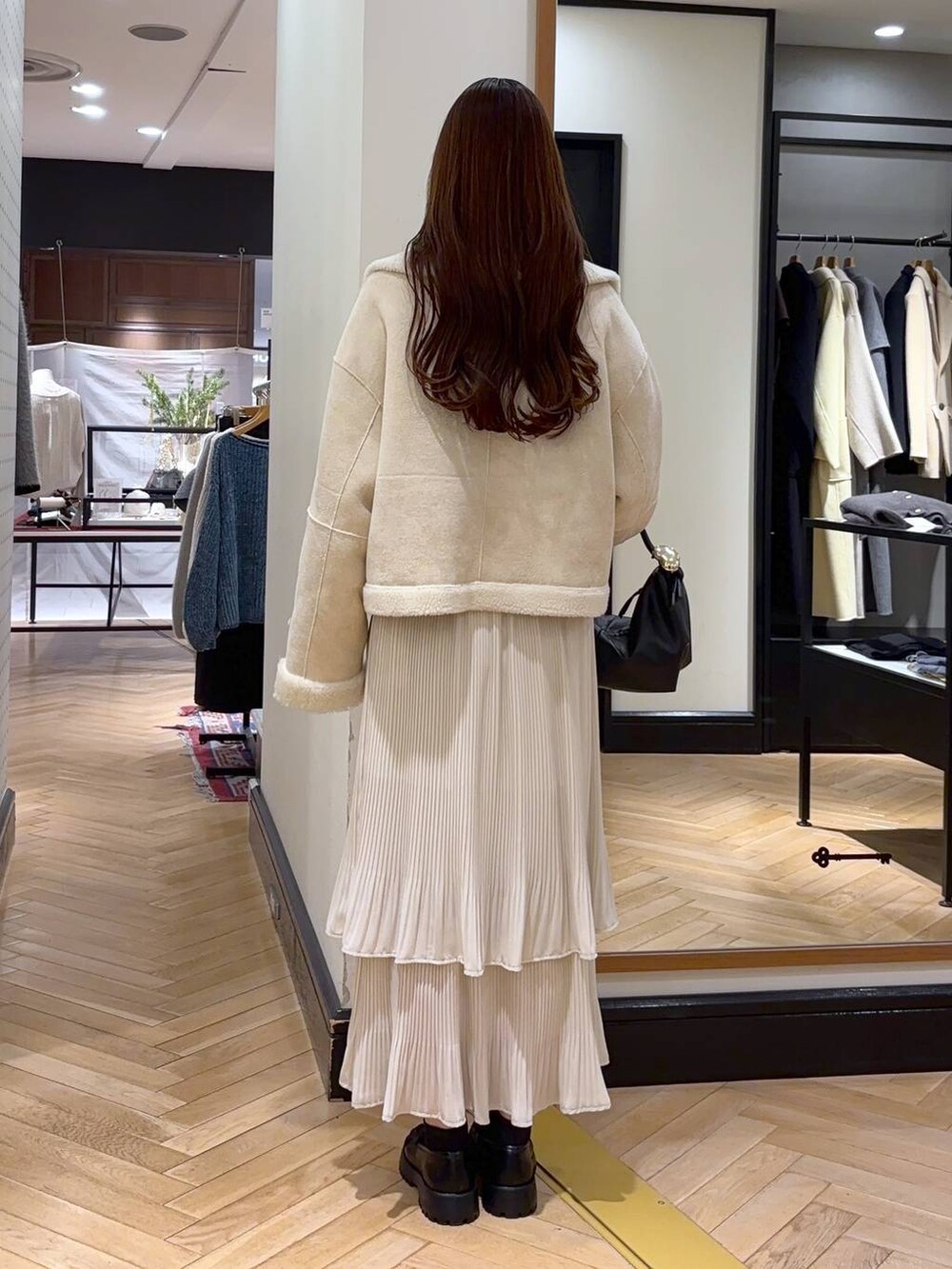 ホワイト系のスカート、ブルー系のカーディガン/ボレロ、ブラック系のショルダーバッグを着用したレディースの冬コーディネートの4枚目の写真