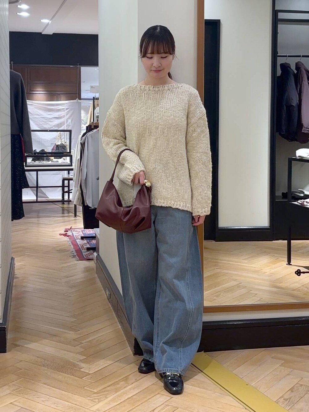 ブルー系のデニムパンツ、ベージュ系のノーカラーコート、ブラック系のショルダーバッグを着用したレディースの秋コーディネートの5枚目の写真