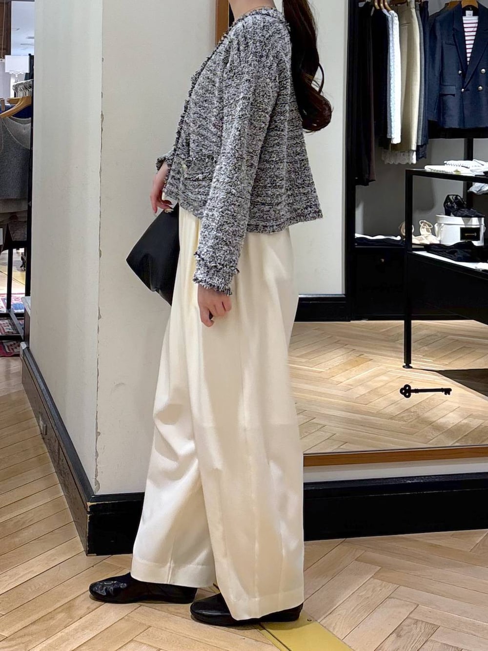 ホワイト系のスラックス、ブラック系のショルダーバッグ、ブラック系のカーディガン/ボレロを着用したレディースの冬コーディネートの4枚目の写真