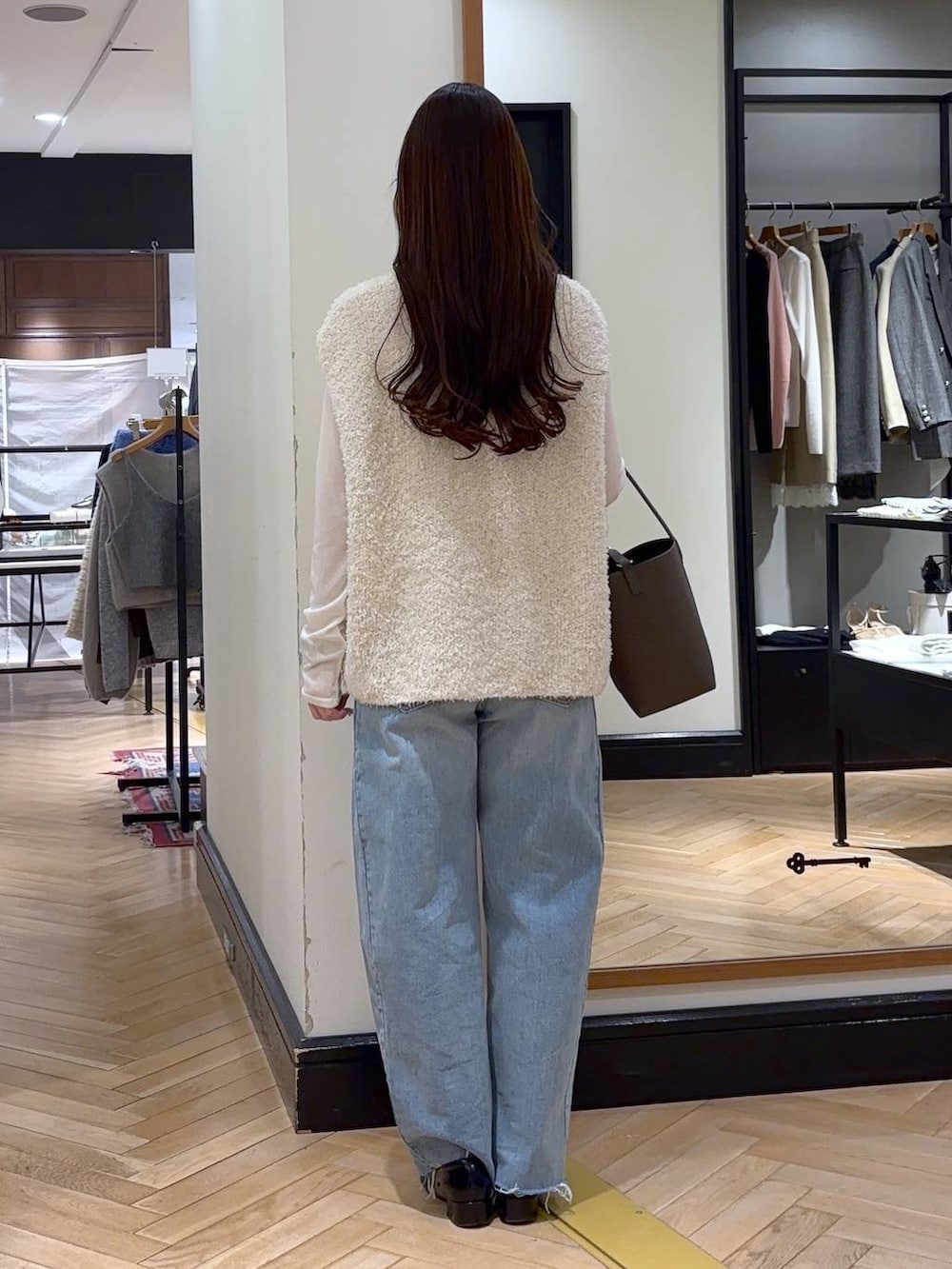 ブラック系のローファー、ブルー系のデニムパンツ、ホワイト系のベストを着用したレディースの冬コーディネートの4枚目の写真