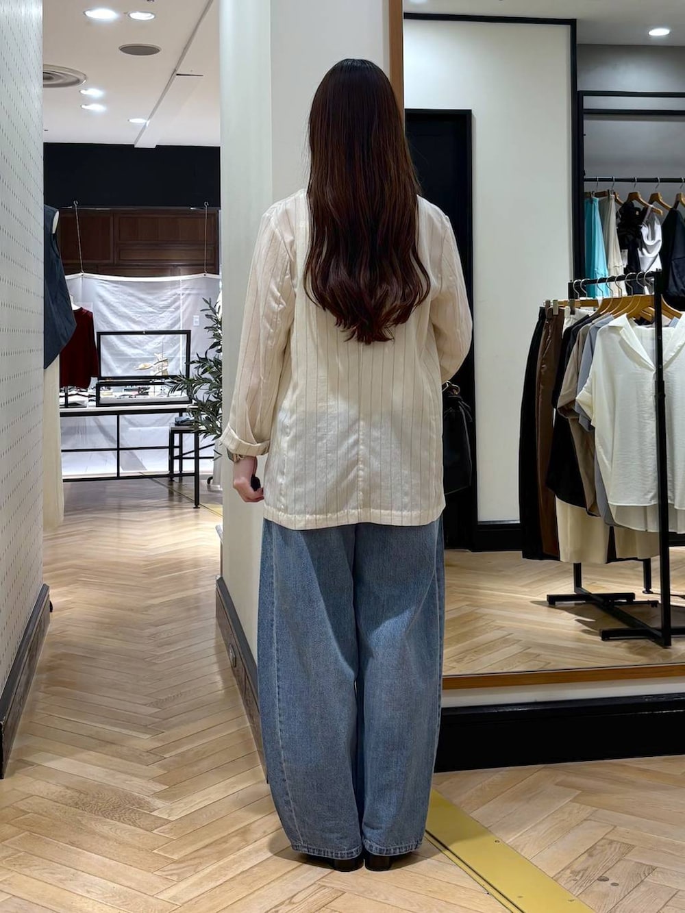 ブルー系のデニムパンツ、ベージュ系のテーラードジャケット、ブラック系のショルダーバッグを着用したレディースの夏コーディネートの4枚目の写真