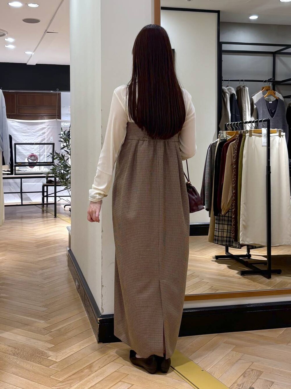レッド系のショルダーバッグ、ブラック系のパンプス、ホワイト系のTシャツ/カットソーを着用したレディースの秋コーディネートの4枚目の写真