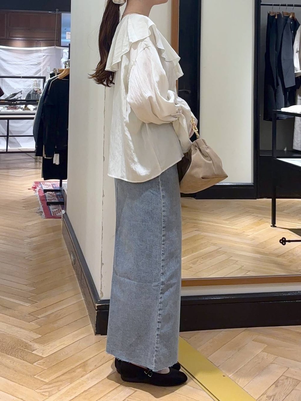 ブルー系のデニムスカート、ブラック系のバレエシューズ、ベージュ系のショルダーバッグを着用したレディースの秋コーディネートの4枚目の写真