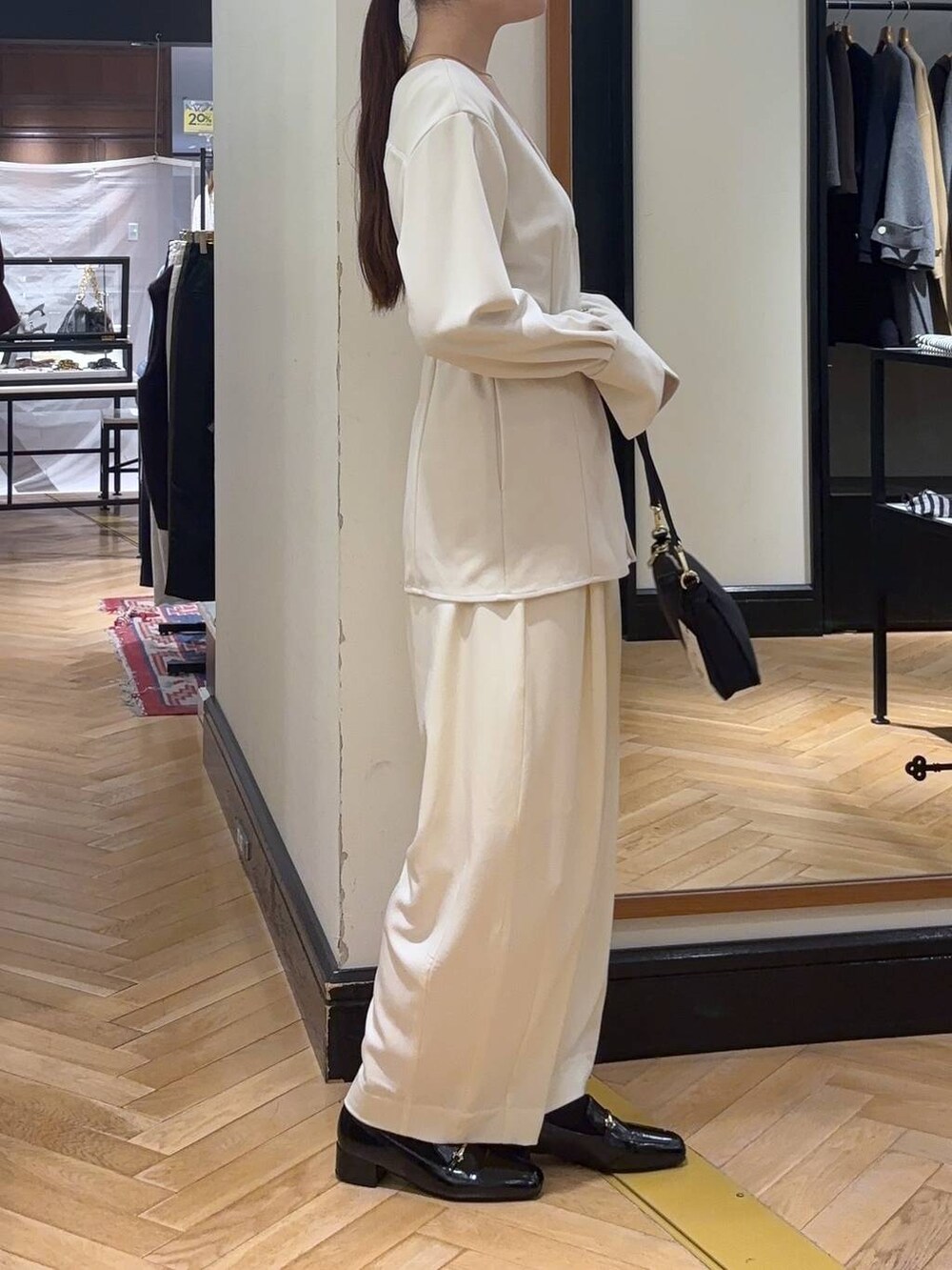 ホワイト系のスラックス、ブラック系のローファー、ブラック系のショルダーバッグを着用したレディースの秋コーディネートの2枚目の写真