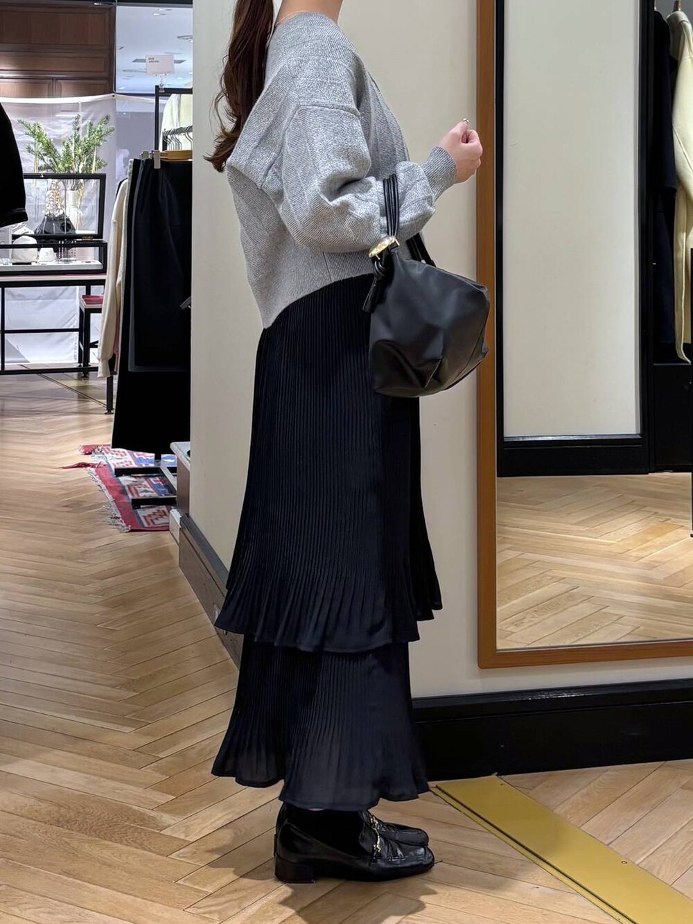 ブラック系のスカート、ブラック系のローファー、ブラック系のショルダーバッグを着用したレディースの冬コーディネートの2枚目の写真