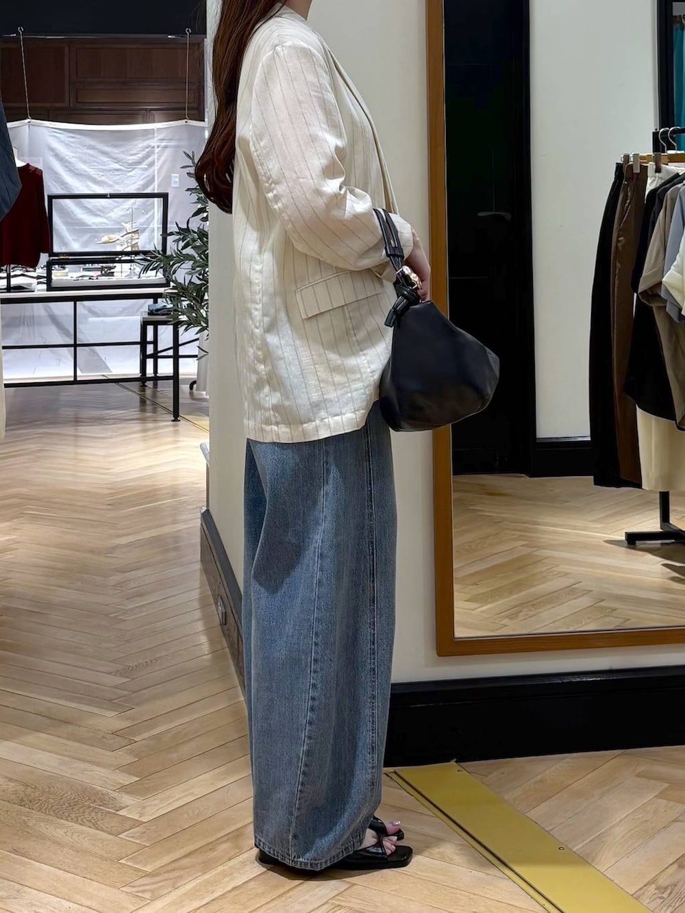 ブルー系のデニムパンツ、ベージュ系のテーラードジャケット、ブラック系のショルダーバッグを着用したレディースの夏コーディネートの2枚目の写真