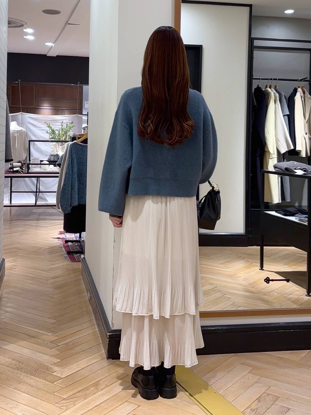 ホワイト系のスカート、ブルー系のカーディガン/ボレロ、ブラック系のショルダーバッグを着用したレディースの冬コーディネートの4枚目の写真