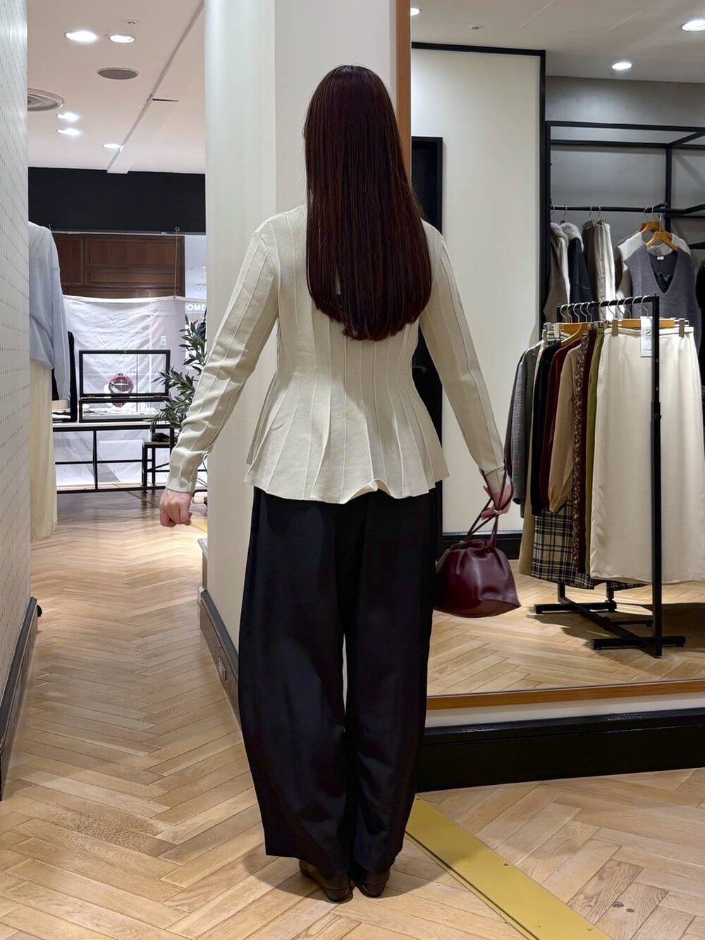 レッド系のショルダーバッグ、ベージュ系のカーディガン/ボレロ、ブラック系のパンプスを着用したレディースの秋コーディネートの4枚目の写真