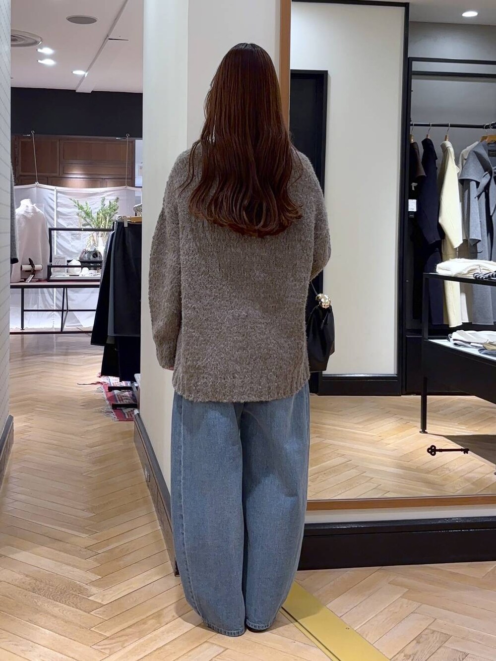 ブルー系のデニムパンツ、ブラック系のローファー、ブラック系のショルダーバッグを着用したレディースの冬コーディネートの3枚目の写真