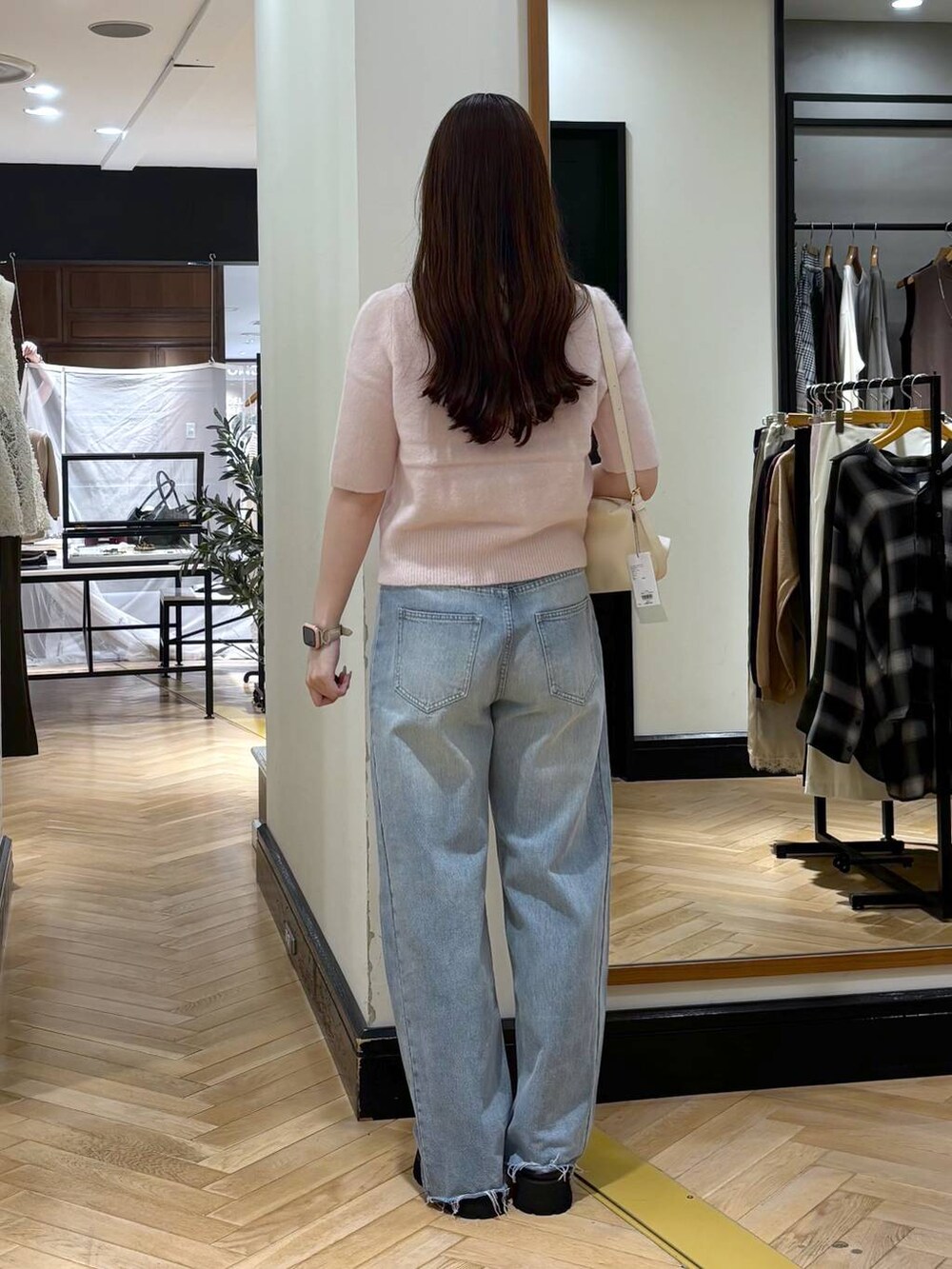 ブラック系のスリッポン、ホワイト系のショルダーバッグ、ブルー系のデニムパンツを着用したレディースの夏コーディネートの4枚目の写真