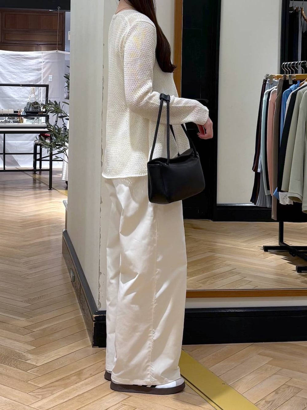 ホワイト系のスラックス、ブラック系のショルダーバッグ、ホワイト系のカーディガン/ボレロを着用したレディースの春コーディネートの2枚目の写真