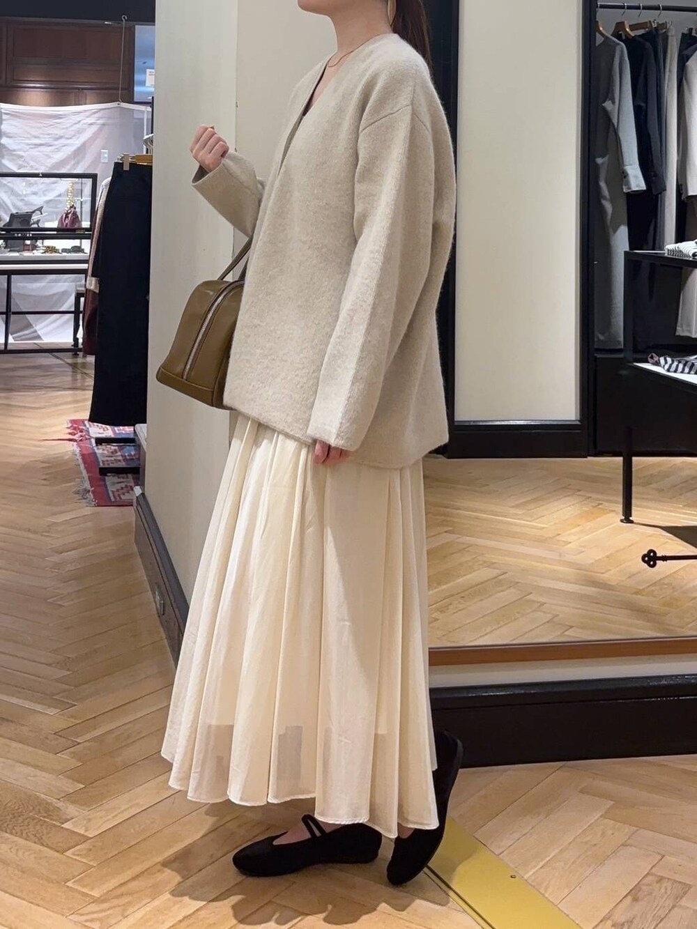 ホワイト系のカーディガン/ボレロ、ブラウン系のボストンバッグ、ブラック系のバレエシューズを着用したレディースの秋コーディネートの2枚目の写真