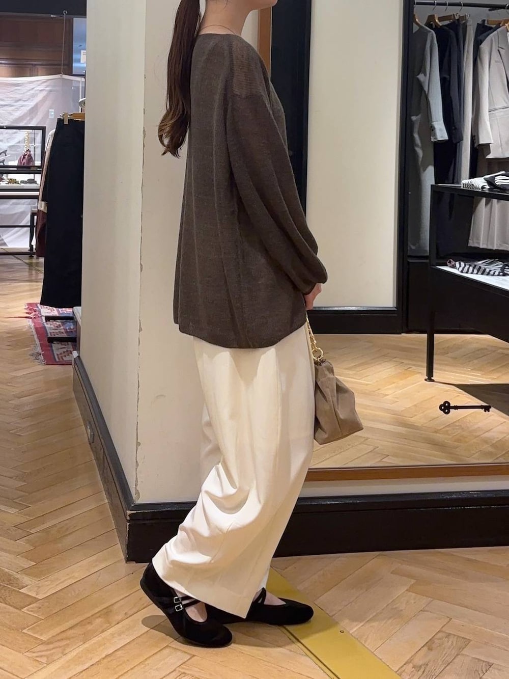 ブラウン系のニット/セーター、ホワイト系のスラックス、ベージュ系のショルダーバッグを着用したレディースの秋コーディネートの2枚目の写真