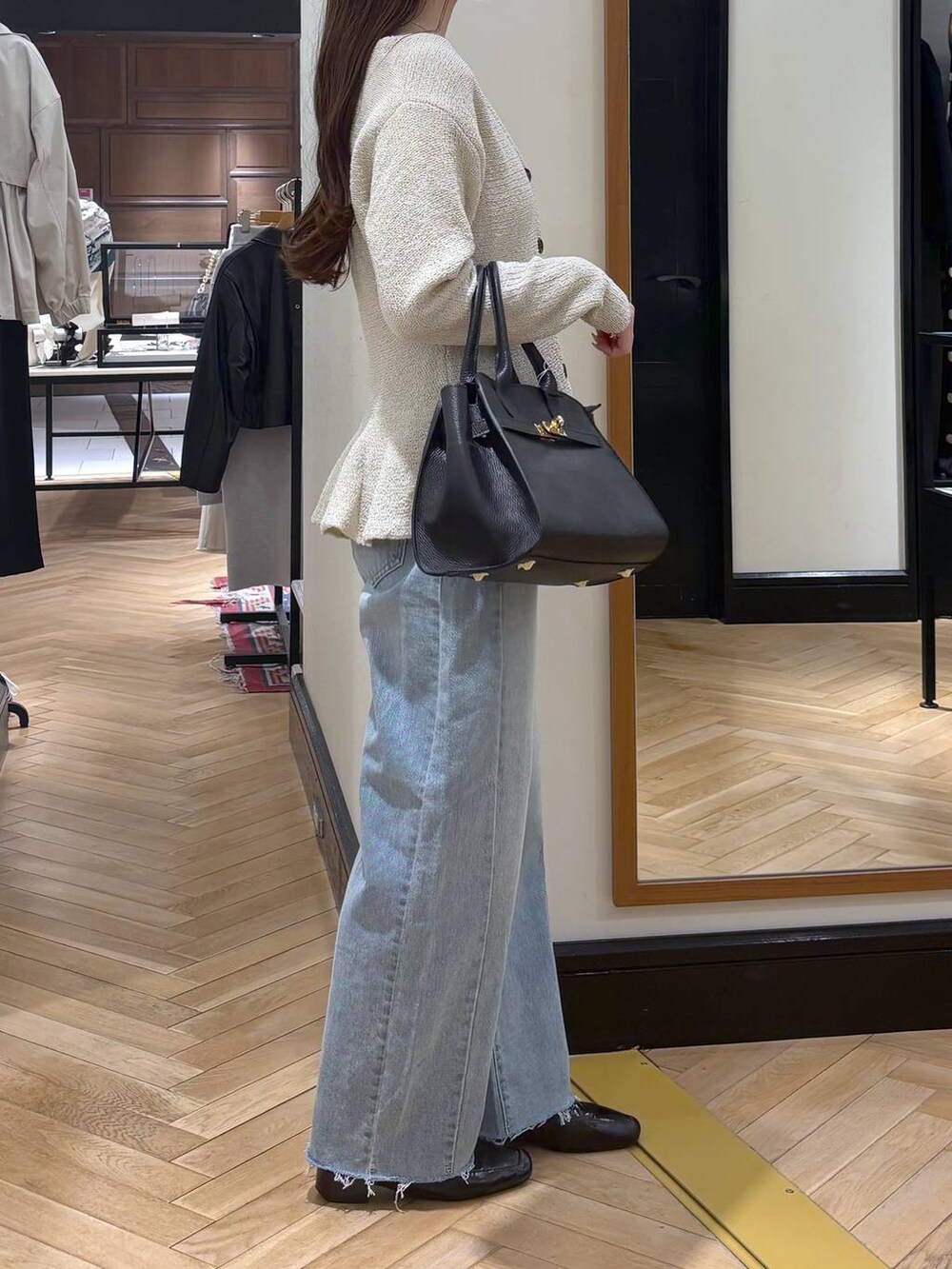 ブラック系のローファー、ブルー系のデニムパンツ、ブラック系のショルダーバッグを着用したレディースの春コーディネートの3枚目の写真