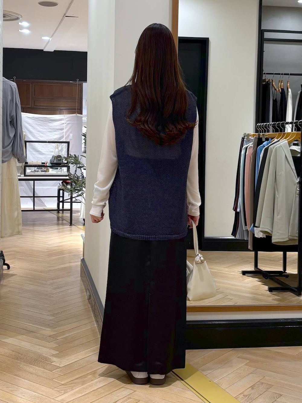 ブラック系のスカート、ブルー系のニット/セーター、ベージュ系のショルダーバッグを着用したレディースの春コーディネートの4枚目の写真