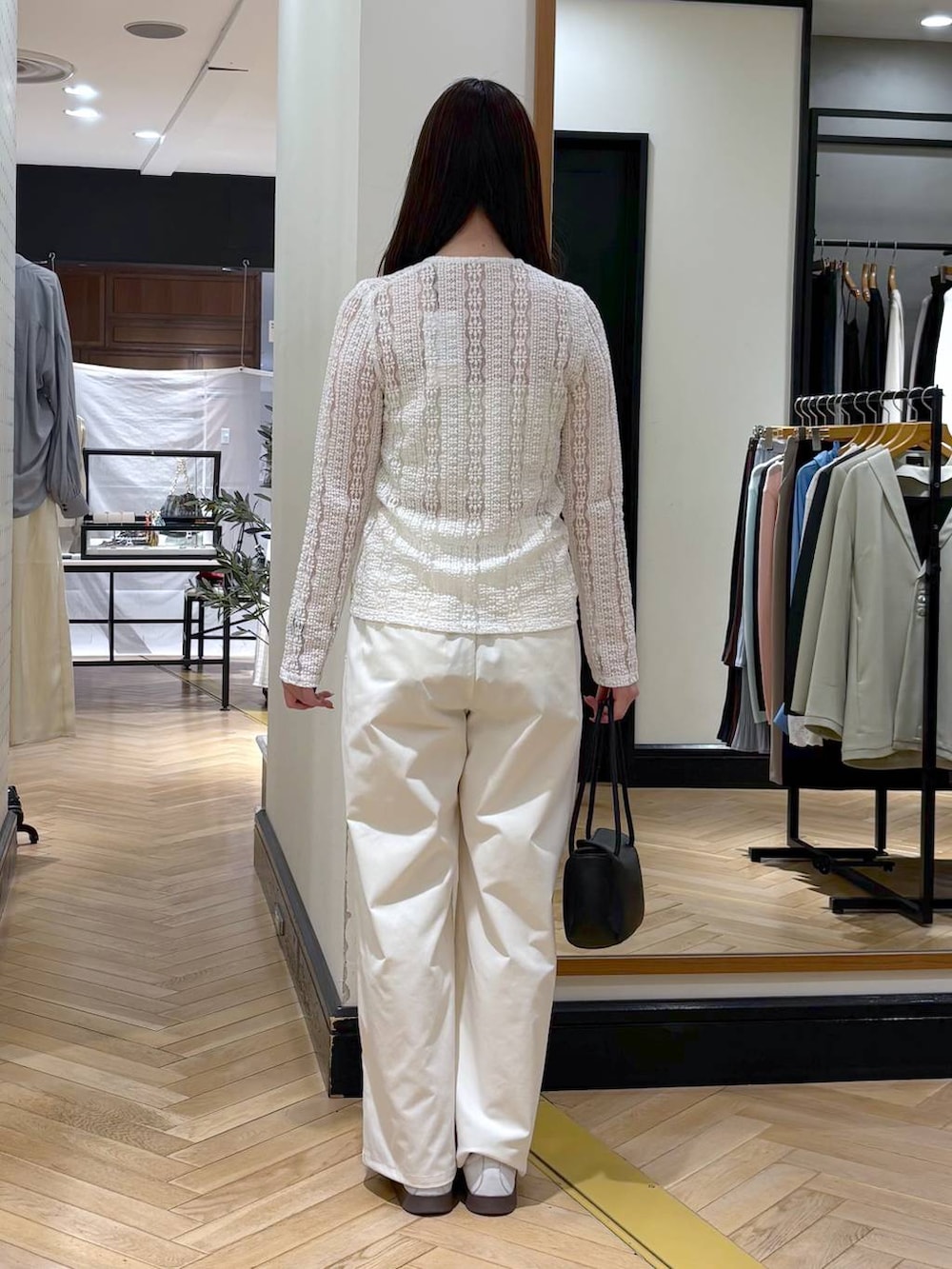 ホワイト系のスラックス、ブラック系のショルダーバッグ、ホワイト系のカーディガン/ボレロを着用したレディースの春コーディネートの6枚目の写真