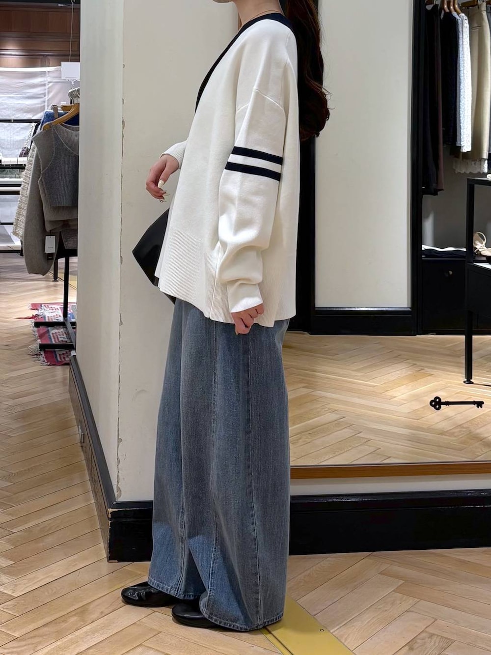 ブルー系のデニムパンツ、ブラック系のカーディガン/ボレロ、ブラック系のショルダーバッグを着用したレディースの冬コーディネートの3枚目の写真