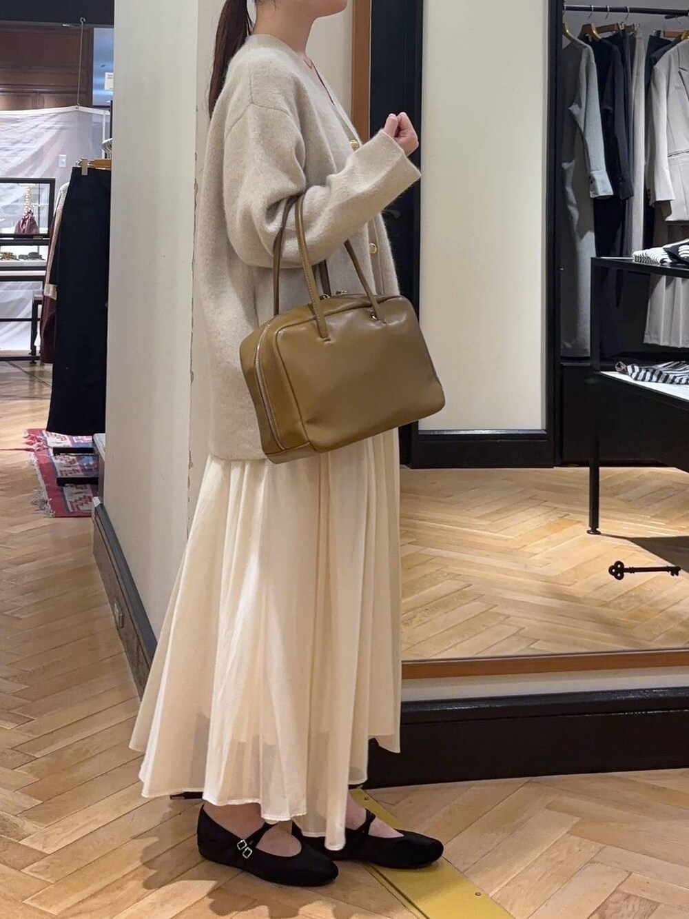 ホワイト系のカーディガン/ボレロ、ブラウン系のボストンバッグ、ブラック系のバレエシューズを着用したレディースの秋コーディネートの3枚目の写真