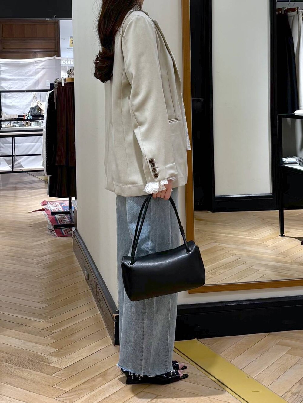 ブルー系のデニムパンツ、ベージュ系のノーカラージャケット、ブラック系のショルダーバッグを着用したレディースの春コーディネートの3枚目の写真