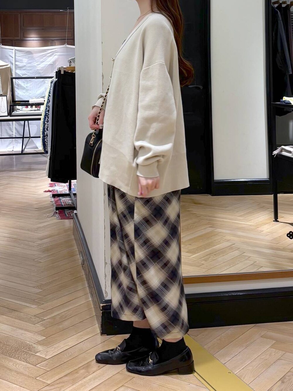 ブラック系のローファー、ホワイト系のカーディガン/ボレロ、ブラック系のショルダーバッグを着用したレディースの冬コーディネートの3枚目の写真