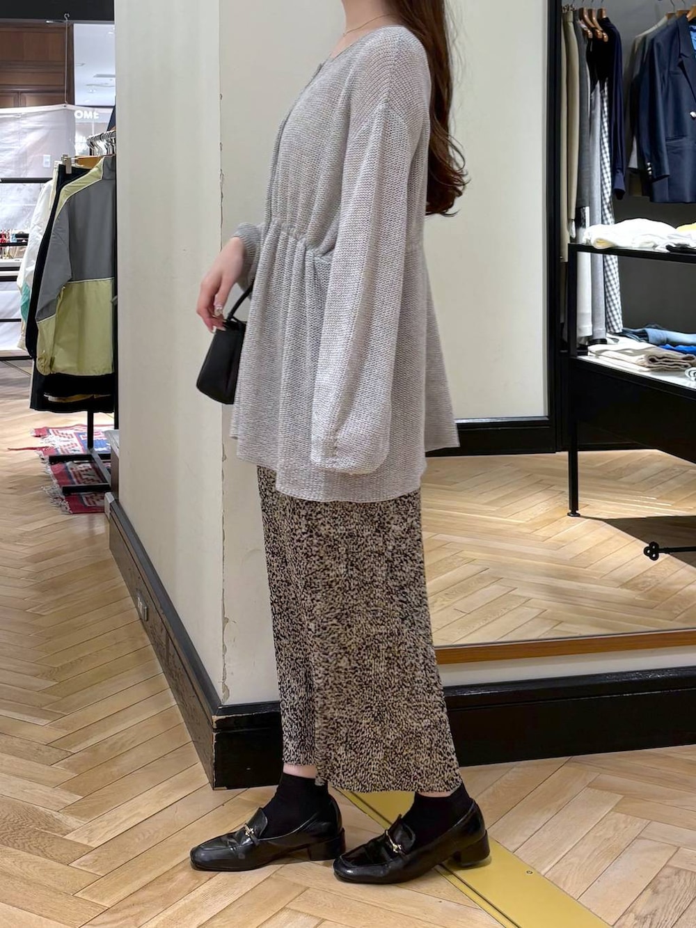 ブラック系のローファー、ベージュ系のスカート、グレー系のカーディガン/ボレロを着用したレディースの春コーディネートの3枚目の写真