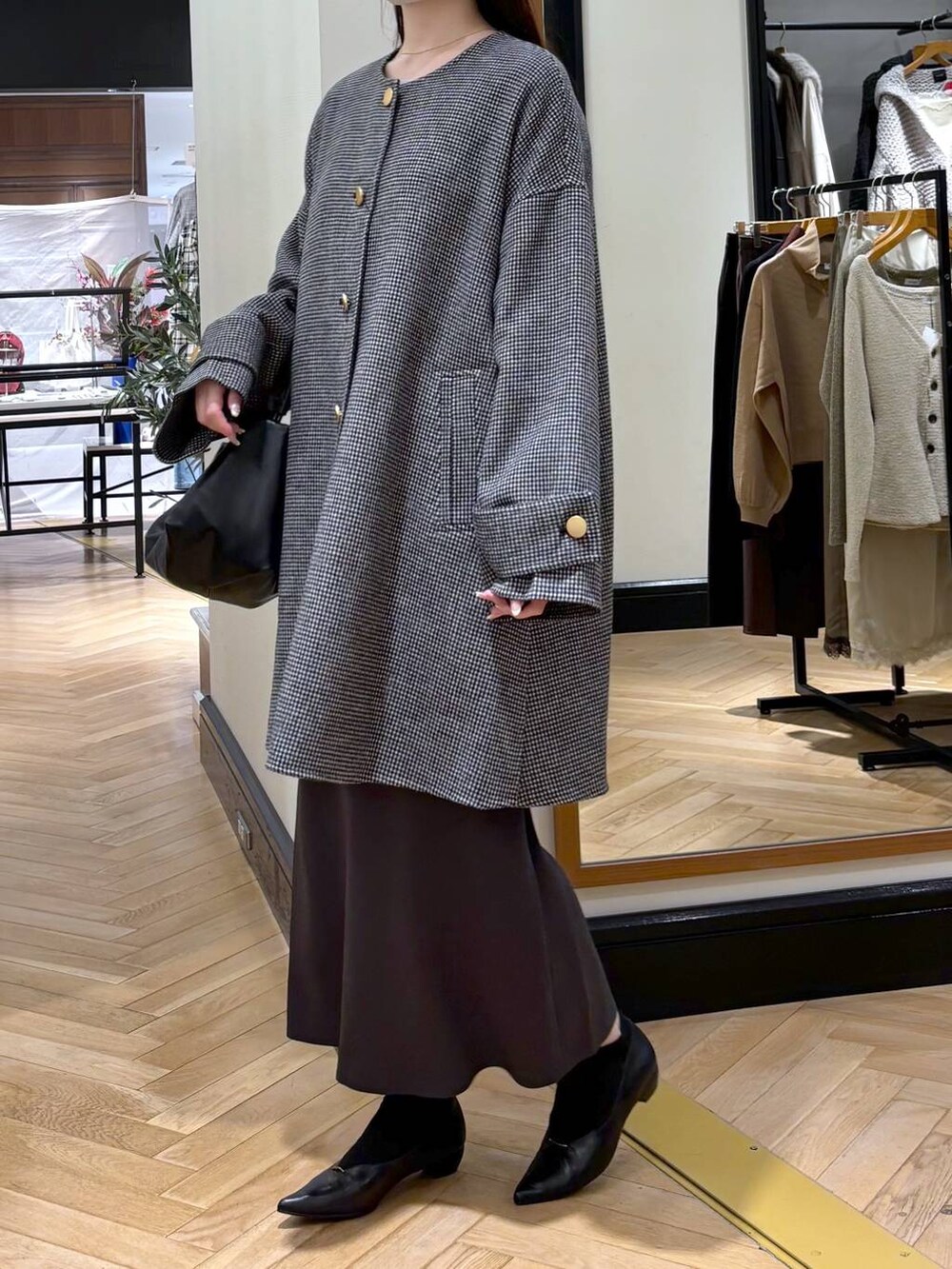 グレー系のスカート、ブラック系のパンプス、その他のノーカラーコートを着用したレディースの秋コーディネートの3枚目の写真