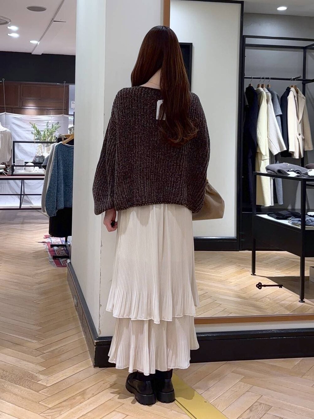 ホワイト系のスカート、ブラウン系のニット/セーター、ベージュ系のショルダーバッグを着用したレディースの冬コーディネートの4枚目の写真