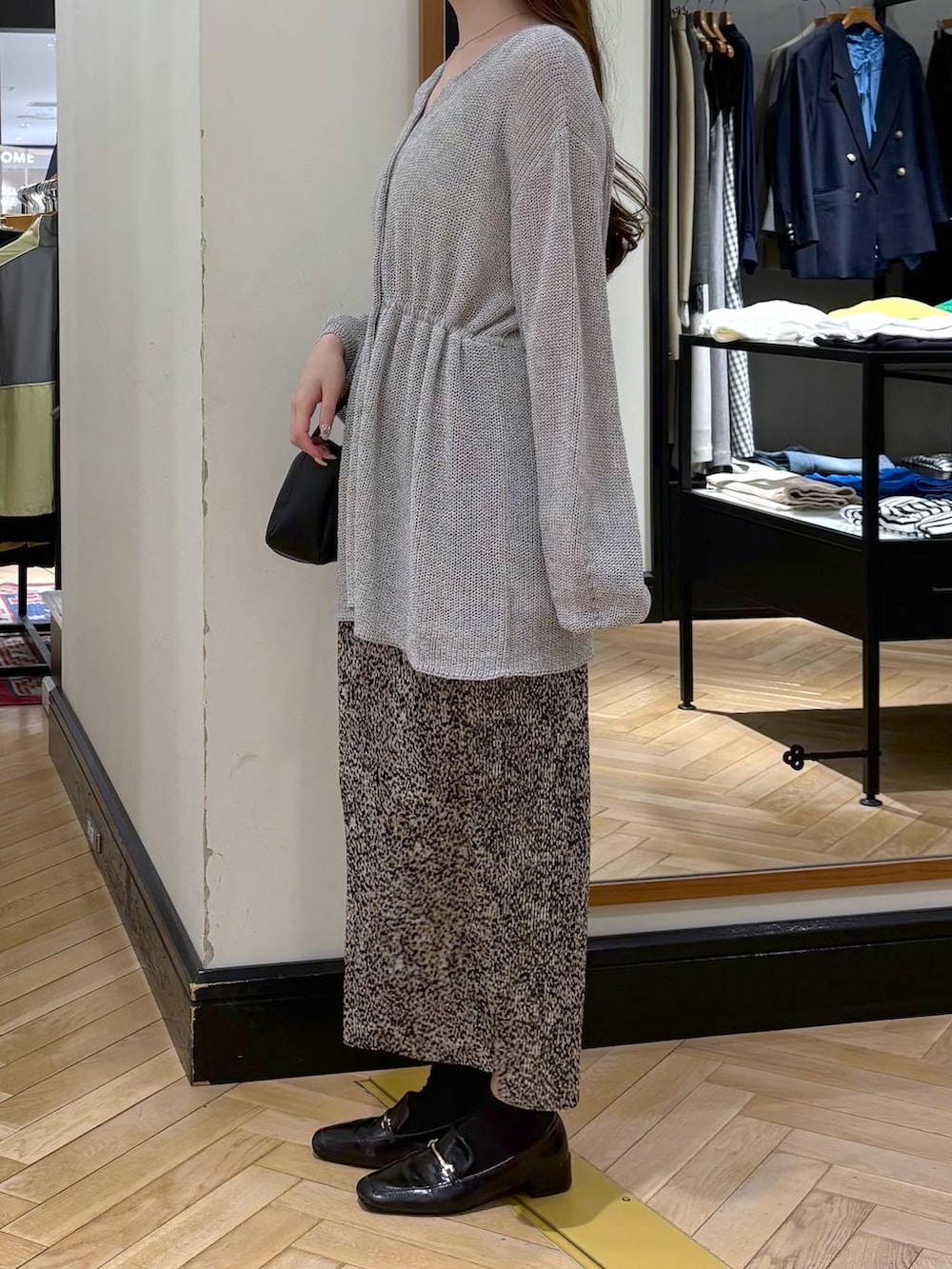 ブラック系のローファー、ベージュ系のスカート、グレー系のカーディガン/ボレロを着用したレディースの春コーディネートの4枚目の写真