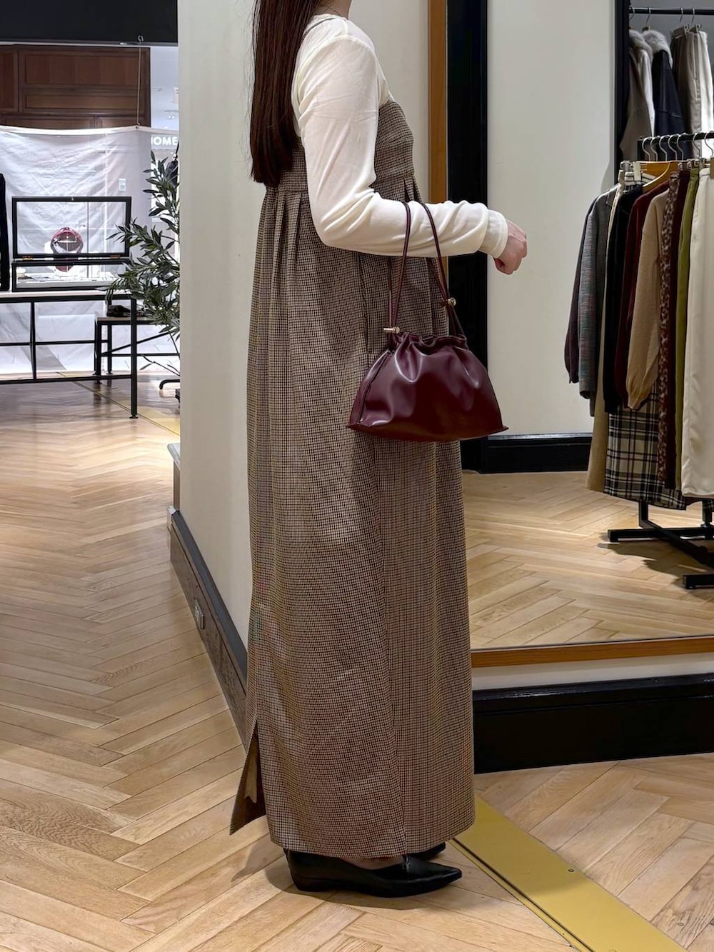 レッド系のショルダーバッグ、ブラック系のパンプス、ホワイト系のTシャツ/カットソーを着用したレディースの秋コーディネートの3枚目の写真