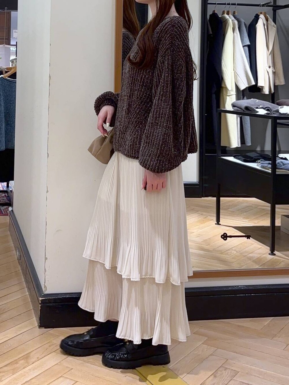 ホワイト系のスカート、ブラウン系のニット/セーター、ベージュ系のショルダーバッグを着用したレディースの冬コーディネートの3枚目の写真