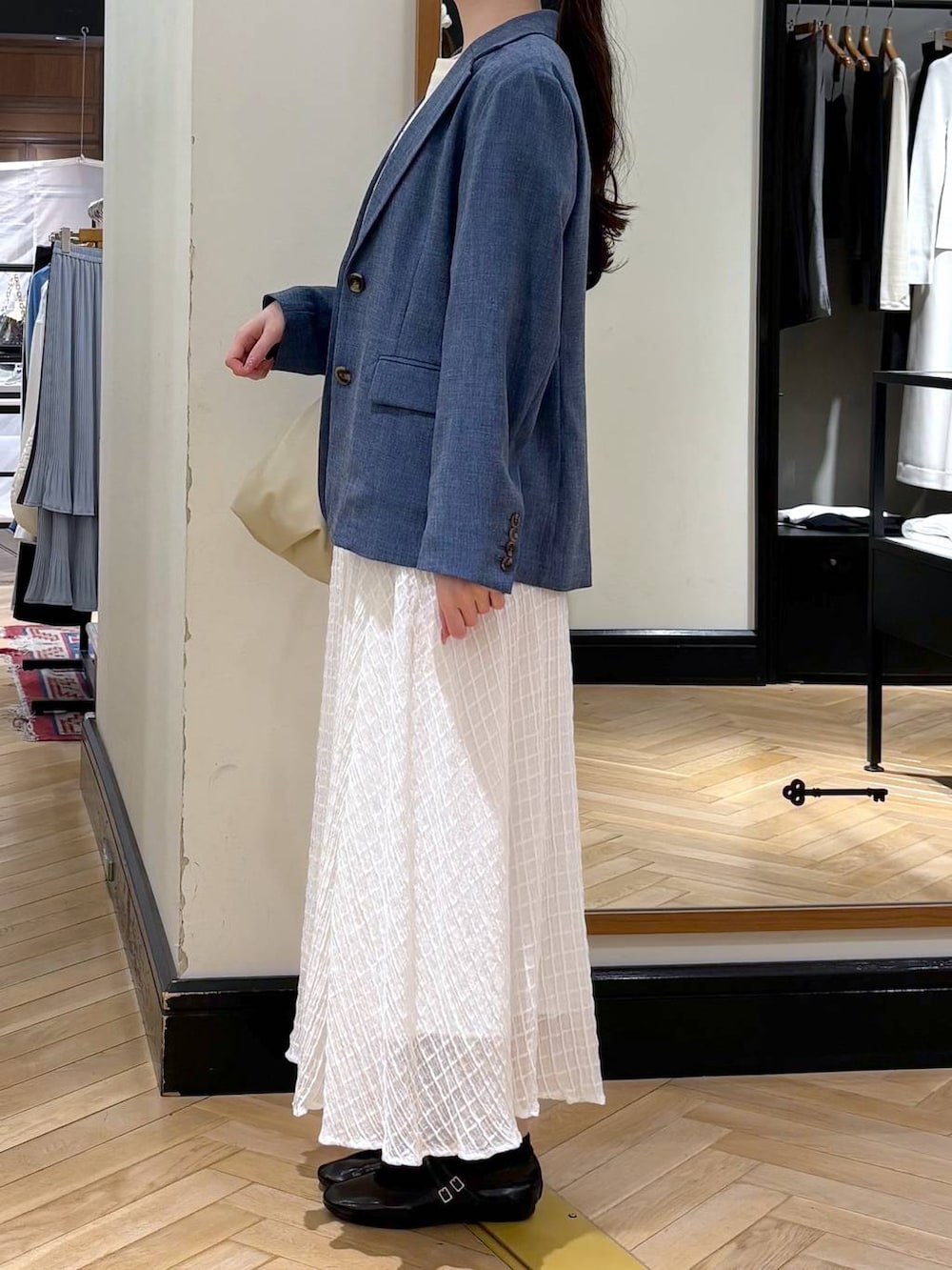 ベージュ系のショルダーバッグ、ブルー系のノーカラージャケット、ブルー系のTシャツ/カットソーを着用したレディースの春コーディネートの3枚目の写真