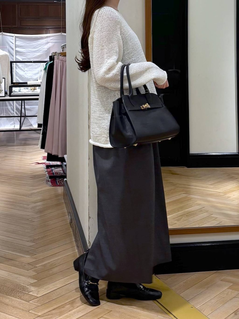 ブラック系のローファー、ブラック系のショルダーバッグ、ホワイト系のニット/セーターを着用したレディースの春コーディネートの2枚目の写真