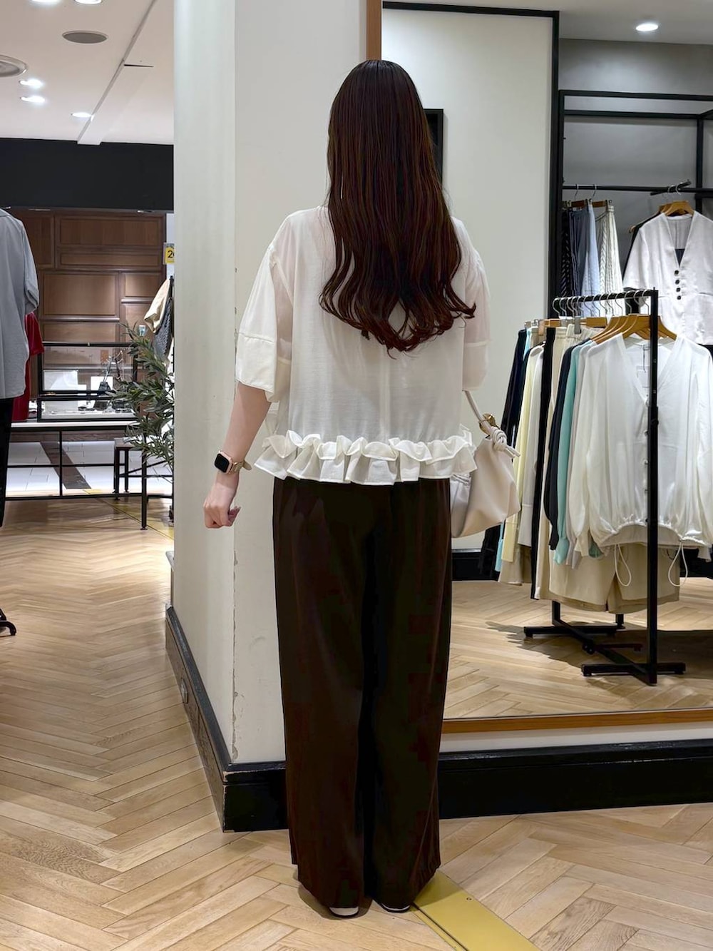 ブラウン系のスラックス、ホワイト系のショルダーバッグ、ホワイト系のパンプスを着用したレディースの春コーディネートの4枚目の写真