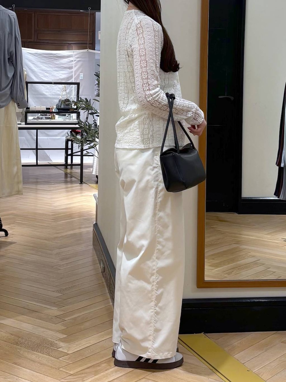 ホワイト系のスラックス、ブラック系のショルダーバッグ、ホワイト系のカーディガン/ボレロを着用したレディースの春コーディネートの2枚目の写真