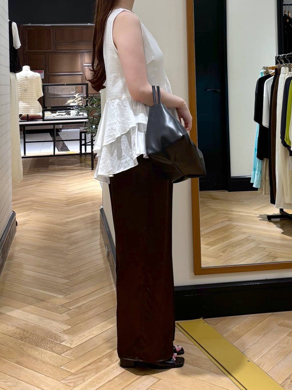 ブラック系のショルダーバッグ、ブラック系のパンプス、ホワイト系のキャミソールを着用したレディースの夏コーディネートの3枚目の写真
